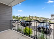 Thumbnail 28 of 50 - A balcony with a black railing overlooks a parking lot.
