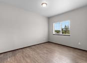 Thumbnail 13 of 50 - Empty room with wooden floor and a window showing trees outside.