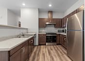 Thumbnail 29 of 50 - A modern kitchen with a stainless steel refrigerator and wooden cabinets.