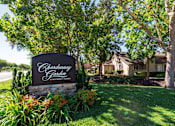 Thumbnail 1 of 18 - A sign for Chardonnay Garden Apartment Homes is surrounded by greenery.