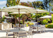 Thumbnail 5 of 18 - A patio with a table and chairs under a striped umbrella.