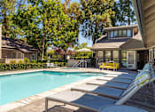 Thumbnail 4 of 18 - A pool with sun loungers and a house in the background.