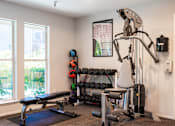 Thumbnail 7 of 18 - A home gym with a bench, weights, and exercise equipment.