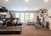 Thumbnail 6 of 18 - A home gym with a treadmill, exercise bike, and other equipment.