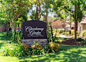 Thumbnail 18 of 18 - A sign for Chardonnay Garden Apartment Homes is surrounded by plants and trees.