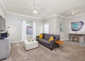 Thumbnail 7 of 33 - a living room with a gray couch and a white ottoman