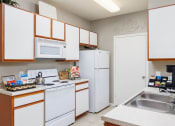 Thumbnail 11 of 33 - a kitchen with white appliances and wooden cabinets