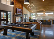 Thumbnail 24 of 34 - A pool table is in the middle of a room with a couch and a bar.
