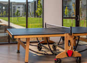 Thumbnail 31 of 34 - A ping pong table with a wooden base and a black top is in the foreground with a view of a grassy area and buildings in the background at The Arvon, Vancouver, WA 98662