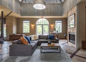 Thumbnail 30 of 39 - A large grey couch with orange and blue pillows sits in a spacious living room.