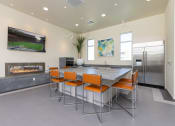 Thumbnail 36 of 59 - a kitchen with a large island with orange chairs and a fireplace at Element 12 Apartments, Henderson NV