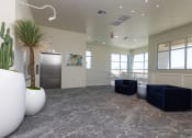 Thumbnail 40 of 59 - a lobby with two blue couches and a cactus in a white vase at Element 12 Apartments, Henderson NV