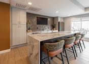 Thumbnail 49 of 68 - A kitchen with a marble countertop and bar stools.