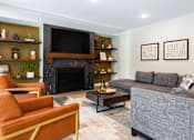 Thumbnail 24 of 35 - A living room with a grey couch, a fireplace, and a television.