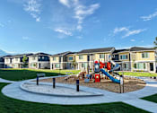 Thumbnail 25 of 26 - A playground with a slide and a sandbox in front of apartment buildings.