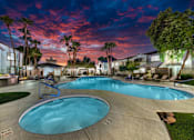 Thumbnail 4 of 52 - A large outdoor swimming pool surrounded by palm trees and lounge chairs.