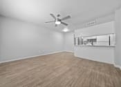 Thumbnail 5 of 21 - an empty living room with a ceiling fan and a kitchen