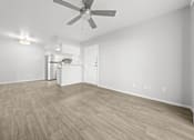 Thumbnail 6 of 21 - an empty living room with a ceiling fan and a kitchen