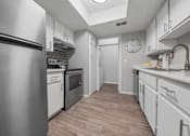 Thumbnail 11 of 21 - a kitchen with white cabinets and stainless steel appliances and a clock on the wall