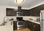 Thumbnail 3 of 30 - A kitchen with dark brown cabinets and stainless steel appliances