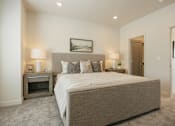 Thumbnail 6 of 20 - A bedroom with a large bed and a small fireplace.