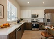 Thumbnail 5 of 20 - A modern kitchen with a refrigerator, sink, and stove.