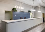 Thumbnail 25 of 25 - A modern office space with a long white counter and a blue backdrop.