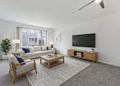Thumbnail 4 of 36 - A living room with a white couch, a wooden coffee table, and a flat-screen TV.