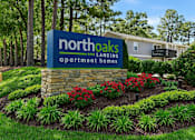 Thumbnail 1 of 48 - A sign for Northoaks Apartment Homes is surrounded by a flower bed.