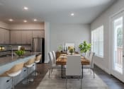 Thumbnail 20 of 31 - a dining room with a wooden table and chairs and a kitchen with a large window
