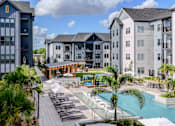 Thumbnail 2 of 59 - A pool area with a slide and sun loungers in front of apartment buildings.