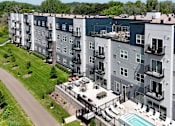 Thumbnail 27 of 35 - Apartment complex with a pool and a green lawn.
