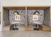 Thumbnail 22 of 57 - A modern lounge area with two booths, each with a table and a bench, and a patterned wallpaper.