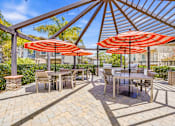 Thumbnail 11 of 57 - A patio with tables and chairs under umbrellas.