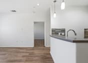 Thumbnail 32 of 57 - A kitchen with a white island and wooden floors.