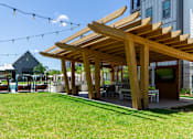 Thumbnail 54 of 59 - A wooden pergola is in the foreground of a sunny day.