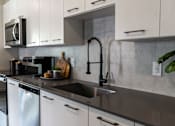 Thumbnail 59 of 59 - A modern kitchen with a black faucet and white cabinets.