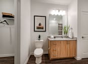 Thumbnail 18 of 36 - A bathroom with a toilet, a mirror, and a wooden cabinet.