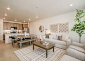 Thumbnail 1 of 23 - Model living room and kitchen at Bloom Rental Living apartments in Fort Collins, CO, featuring wood grain floor paneling.