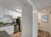 Thumbnail 8 of 25 - an empty kitchen with white cabinets and a stainless steel refrigerator