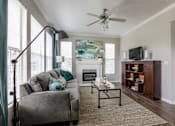Thumbnail 2 of 14 - Living room with grey couch at The Retreat at Fox Hollow apartments for rent in Lakewood, CO.