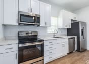 Thumbnail 51 of 59 - a kitchen with white cabinets and black appliances and a stainless steel refrigerator
