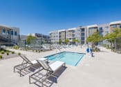Thumbnail 55 of 59 - a swimming pool with lounge chairs around it in front of a building at Element 12 Apartments, Henderson NV