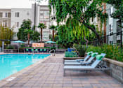 Thumbnail 16 of 32 - a swimming pool with two chaise lounge chairs     and some buildings