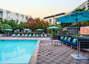 Thumbnail 17 of 32 - a swimming pool with blue chairs and umbrellas and a building in the background