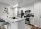 Thumbnail 2 of 30 - A modern kitchen with white cabinets and stainless steel appliances.