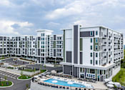 Thumbnail 8 of 28 - A large white building with a pool in front.