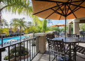 Thumbnail 24 of 28 - a patio with a table and chairs and a pool in the background