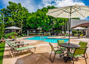 Thumbnail 13 of 33 - Poolside area with table and chairs at Eagle Point Apartments, Albuquerque