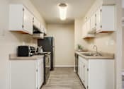 Thumbnail 3 of 13 - A kitchen with white cabinets and a black refrigerator.